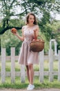 beautiful young woman with wicker basket with ripe apples