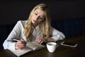 Beautiful young woman work in caffe. Woman writing and using phone while sitting in restaurant Royalty Free Stock Photo