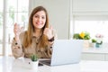 Beautiful young woman working with computer takes a break to drink glass of water happy with big smile doing ok sign, thumb up Royalty Free Stock Photo