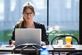 Beautiful young woman working with her laptop while having breakfast in a coffee shop. Royalty Free Stock Photo