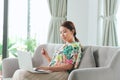 Beautiful young woman working on laptop computer while sitting at the living room, showing credit card Royalty Free Stock Photo