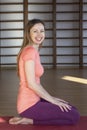 Beautiful young woman working out in loft interior, doing yoga exercise on blue mat, arm balance exercise with crossed legs Royalty Free Stock Photo