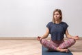 Beautiful young woman working out in loft interior on white background with copy space, doing yoga exercise on mat, Sitting in Royalty Free Stock Photo