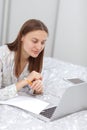 Beautiful young woman working, using laptop computer and makes notes in the bedroom at home. Freelancer. Writing, typing. Girl Royalty Free Stock Photo