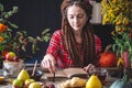 Beautiful young woman writes autumn dreams in a notebook. Fall table with flowers. Concept of autumn romantic mood