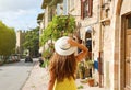 Beautiful young woman with yellow dress and hat walking in typical Assisi street, Italy. Rear view of happy cheerful girl visiting Royalty Free Stock Photo