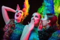 Beautiful young women in carnival and masquerade costume in colorful neon lights on black background