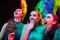 Beautiful young women in carnival and masquerade costume in colorful neon lights on black background