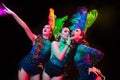 Beautiful young women in carnival and masquerade costume in colorful neon lights on black background