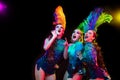 Beautiful young women in carnival and masquerade costume in colorful neon lights on black background