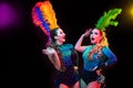 Beautiful young women in carnival and masquerade costume in colorful neon lights on black background