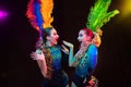 Beautiful young women in carnival and masquerade costume in colorful neon lights on black background
