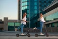 Beautiful young women is enjoying sunny summer day while riding around the city on electro kick scooters. Lifestyle. Royalty Free Stock Photo