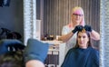 Woman with hairdresser looking hair dye sample in mirror Royalty Free Stock Photo