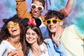 Happy friends having fun in the park with multicolored smoke bombs