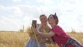 Beautiful young women in meadow collect flowers and are photographed on a smartphone in meadow. Ecotourism. Two happy Royalty Free Stock Photo