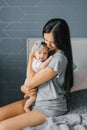 Beautiful young woman mother holds her daughter in her arms, looks at her and smiles at her Royalty Free Stock Photo