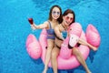 Beautiful young women showing drinks on the pool