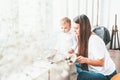 Beautiful young woman with small child sit near the window Royalty Free Stock Photo