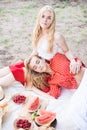 Beautiful young women talking, smiling and gesturing while having picnic outdoors at park. Royalty Free Stock Photo