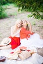 Beautiful young women talking, smiling and gesturing while having picnic outdoors at park. Royalty Free Stock Photo