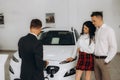 Beautiful young woman is talking to handsome car dealership worker while choosing a car in dealership. Royalty Free Stock Photo