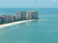 beautiful zoom drone capture of a beach lined with tourists enjoying the sun, apartment buildings, and hotels