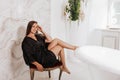 Beautifull brunette woman with long hair in a silk negligee sitting on floor near the bathroom Royalty Free Stock Photo