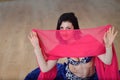 Beautifull caucasian woman in costume for belly-dance is dancing indoors at fitness class covered in silk veil Royalty Free Stock Photo