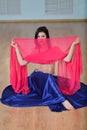 Beautifull caucasian woman in costume for belly-dance is dancing indoors at fitness class covered in silk veil Royalty Free Stock Photo