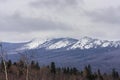 Beautifull cloudy sunrise in the mountains with snow ridge. Cloud and mist surrounding snow-covered mountain. Taganay. South Ural