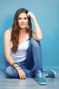 Beautifull smiling woman sitting on floor against blue wall Royalty Free Stock Photo