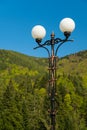 A Beautifully Crafted Street Lamp Facing the Blue Sky and Green Mountains