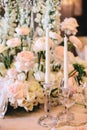 A beautifully decorated banquet table with a floral composition of white roses and buttercups, candles and wine glasses Royalty Free Stock Photo