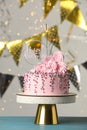 Beautifully decorated birthday cake and party decor on turquoise wooden table against blurred festive lights Royalty Free Stock Photo