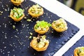 Beautifully decorated catering banquet table with different food snacks and appetizers with sandwich, caviar, fresh fruits on corp