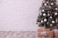 Beautifully decorated Christmas tree and gift boxes near white brick wall, space for text Royalty Free Stock Photo