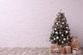 Beautifully decorated Christmas tree and gift boxes  near white brick wall, space for text Royalty Free Stock Photo