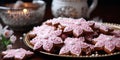 Beautifully decorated pink gingerbreads on a golden plate and candles on a dark background. Christmas backgrpund