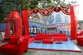 Beautifully decorated red sofas or couch ready for the guests sitting at a engagement ceremony venue in backyard, wedding event