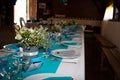 Beautifully decorated white blue festive table with plates and glasses and bouquet of flowers in restaurant Royalty Free Stock Photo