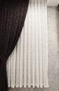 Beautifully draped long curtain on the window in the room. Close up of piled curtain. Luxury curtain, home decor. Brown panels. Wh