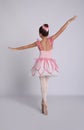 Beautifully dressed little ballerina dancing on grey background, back view