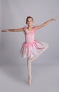 Beautifully dressed little ballerina dancing on grey background