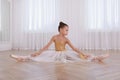 Beautifully dressed little ballerina stretching in studio