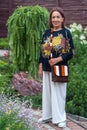 Beautifully dressed, stylish woman of eighty or ninety years old in garden with flowers in summer