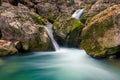 Beautifully flowing water between stones in the mountains, boulders covered with moss