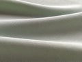 Beautifully folded light green fabric. Soft pleasant waves and flounces on textiles. Close-up. Drapery for curtains