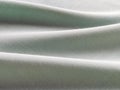Beautifully folded light green fabric. Soft pleasant waves and flounces on textiles. Close-up. Drapery for curtains