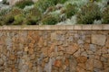 Beautifully folded retaining wall with a granite attic with small joints. brown beige yellow irregular gneiss stone holding a slop Royalty Free Stock Photo